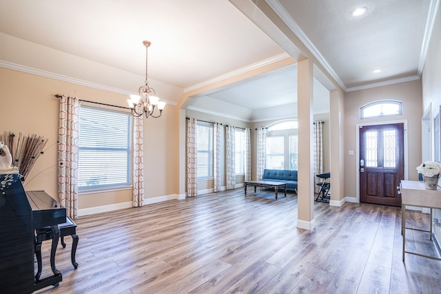 entrance foyer featuring light wood finished floors, an inviting chandelier, baseboards, and ornamental molding