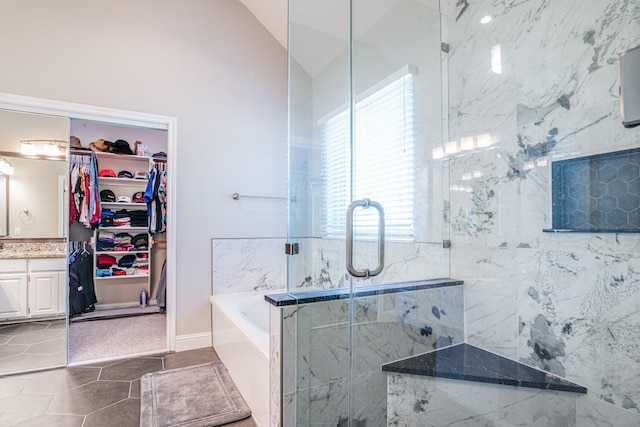 bathroom featuring a marble finish shower, a spacious closet, lofted ceiling, a bath, and vanity