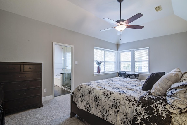 carpeted bedroom with visible vents, baseboards, lofted ceiling, ensuite bathroom, and a ceiling fan