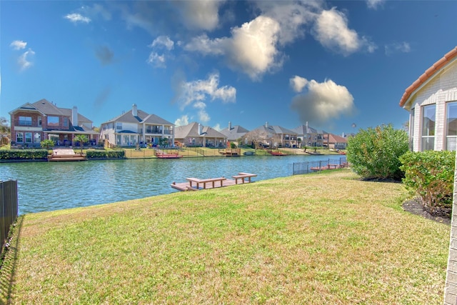 view of dock featuring a residential view, a water view, a lawn, and fence