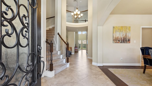 tiled foyer featuring a notable chandelier, arched walkways, a high ceiling, baseboards, and stairs