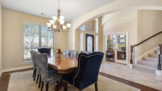 dining area with visible vents, wood finished floors, an inviting chandelier, baseboards, and stairs