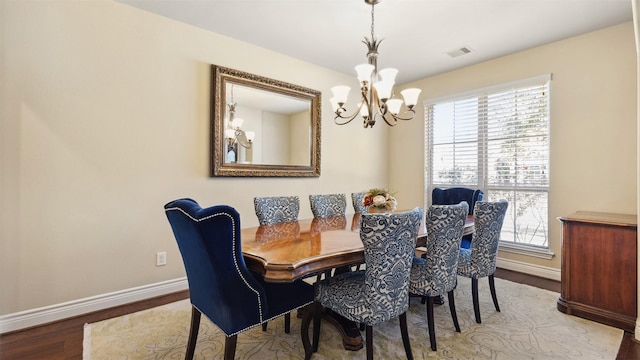 dining area with visible vents, a healthy amount of sunlight, an inviting chandelier, and wood finished floors