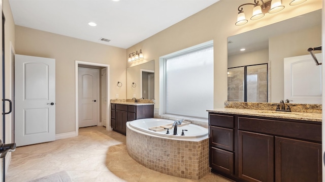 bathroom with visible vents, a garden tub, two vanities, a sink, and a shower stall