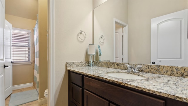 full bathroom with toilet, vanity, and baseboards