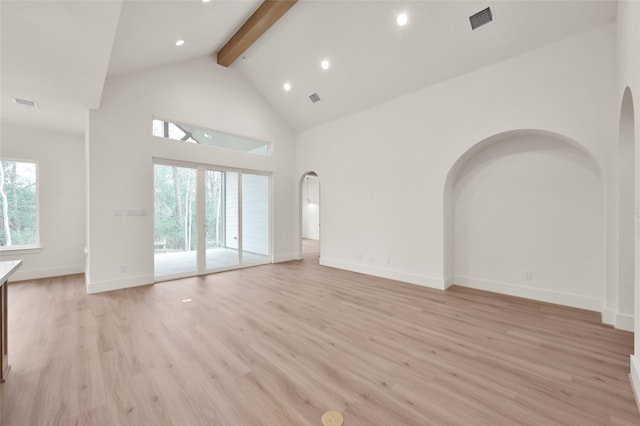 unfurnished living room featuring light wood-type flooring, beam ceiling, visible vents, and arched walkways