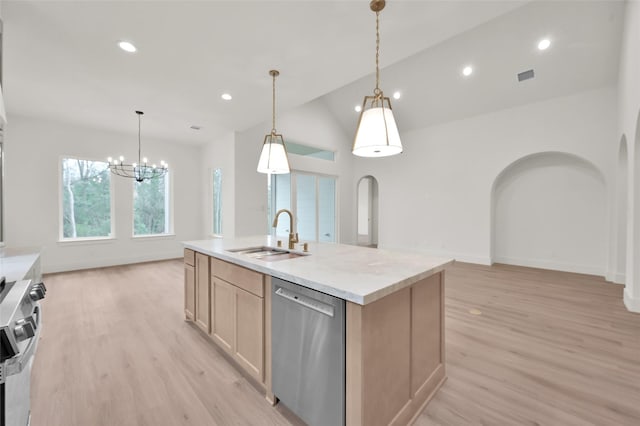 kitchen with appliances with stainless steel finishes, arched walkways, a sink, and light wood finished floors