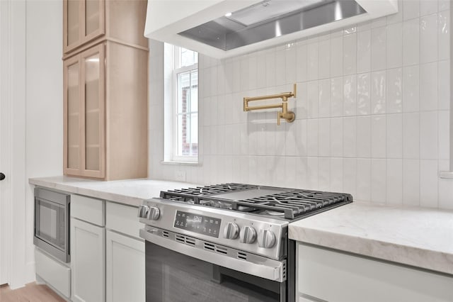 kitchen featuring light stone counters, appliances with stainless steel finishes, extractor fan, and glass insert cabinets