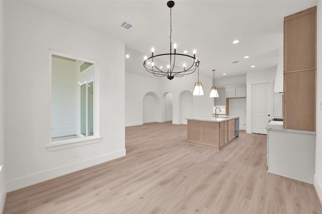 kitchen with arched walkways, visible vents, baseboards, light countertops, and light wood-type flooring