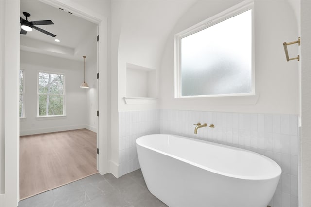 bathroom with tile walls, recessed lighting, wainscoting, ceiling fan, and a freestanding tub