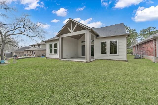 rear view of house featuring central air condition unit, a shingled roof, a lawn, and a patio