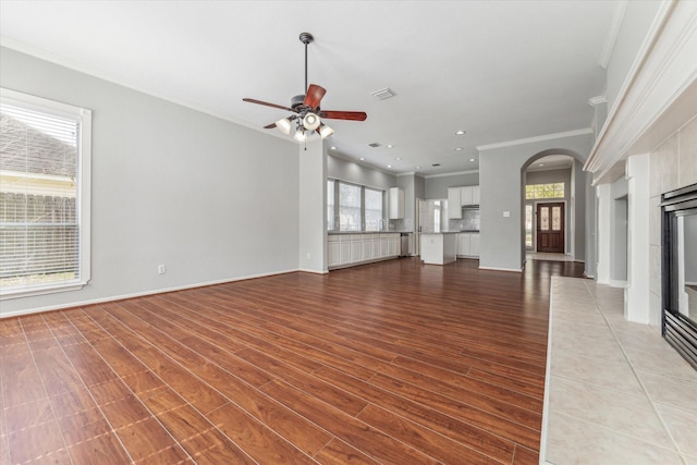 unfurnished living room featuring visible vents, crown molding, a tiled fireplace, and wood finished floors