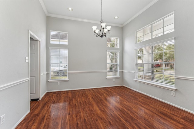 empty room with ornamental molding, wood finished floors, and baseboards