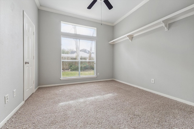 empty room featuring a ceiling fan, carpet, baseboards, and crown molding