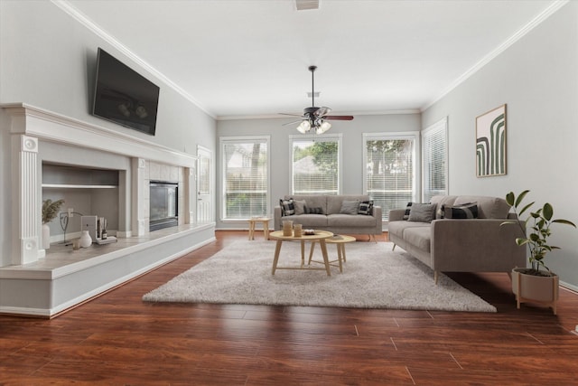 living room with crown molding, a tiled fireplace, and wood finished floors