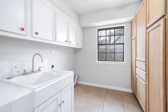 laundry area featuring cabinet space, light tile patterned floors, baseboards, a sink, and electric dryer hookup