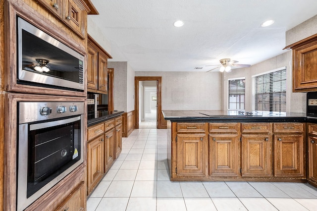 kitchen with stainless steel appliances, dark countertops, and a peninsula