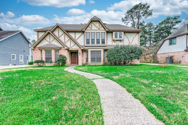 english style home featuring central AC unit, a front lawn, and brick siding