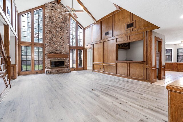 unfurnished living room featuring a ceiling fan, a brick fireplace, visible vents, and light wood-style floors