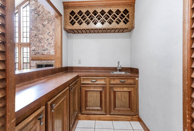 bar featuring light tile patterned floors, indoor wet bar, and a sink