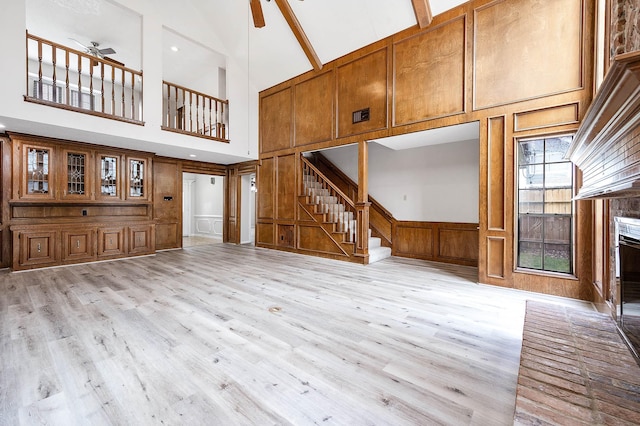 unfurnished living room featuring a fireplace, ceiling fan, a decorative wall, and stairs