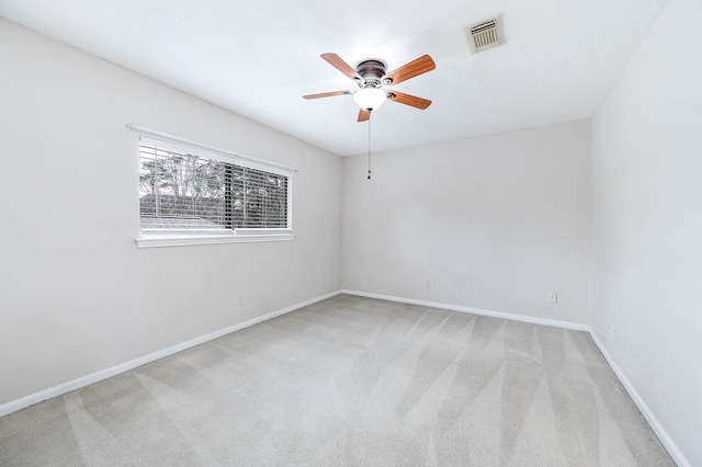 carpeted empty room featuring a ceiling fan, visible vents, and baseboards