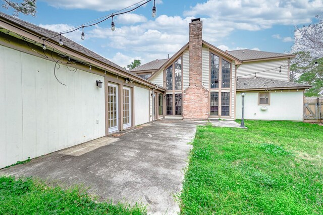 rear view of house featuring a patio area, a lawn, a chimney, and fence