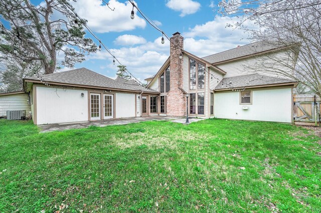 back of house featuring central AC, a yard, a chimney, and fence