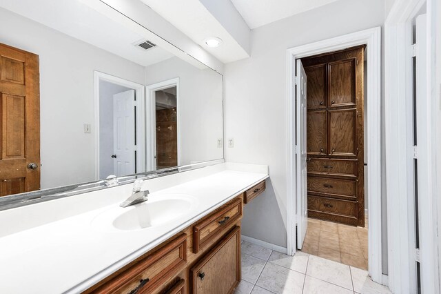 bathroom with baseboards, vanity, visible vents, and tile patterned floors