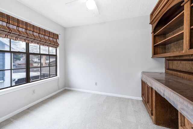 interior space featuring light carpet, a textured ceiling, a ceiling fan, and baseboards