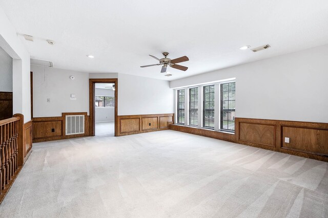 unfurnished room with a wainscoted wall, visible vents, and light colored carpet