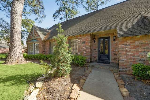 property entrance with brick siding and a lawn