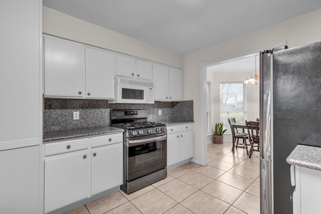 kitchen featuring stainless steel appliances, backsplash, white cabinetry, light tile patterned flooring, and a chandelier