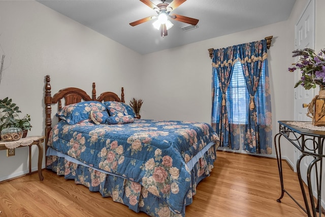 bedroom featuring visible vents, ceiling fan, baseboards, and wood finished floors