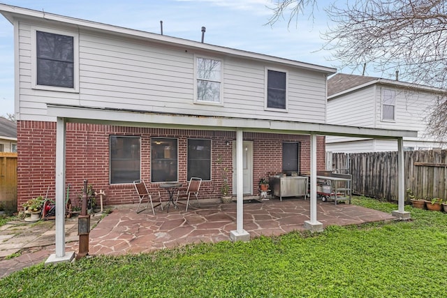 back of house featuring brick siding, a patio area, and fence