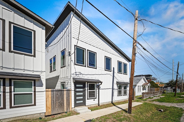 view of front of house featuring board and batten siding and fence