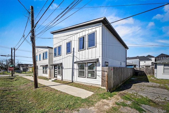 view of front facade featuring a residential view, fence, and board and batten siding