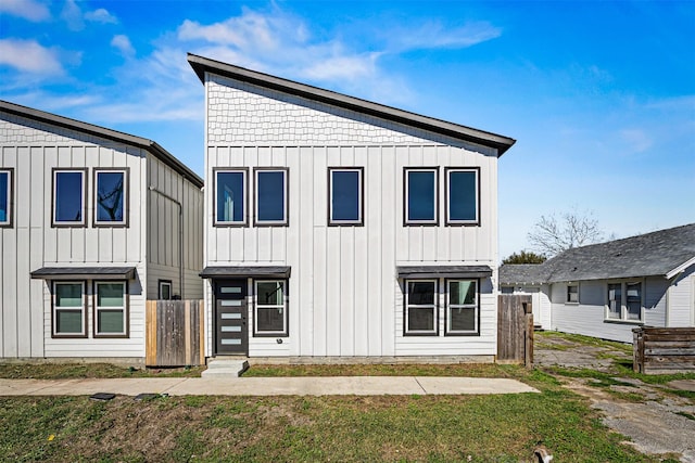 modern farmhouse featuring board and batten siding and fence