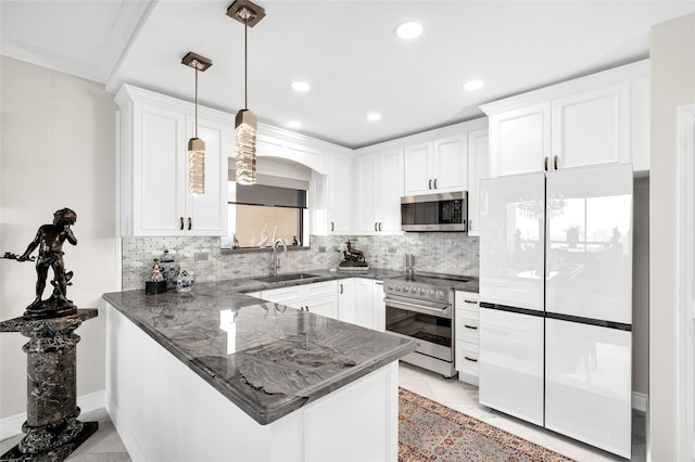 kitchen featuring stainless steel appliances, a peninsula, a sink, white cabinetry, and dark stone counters