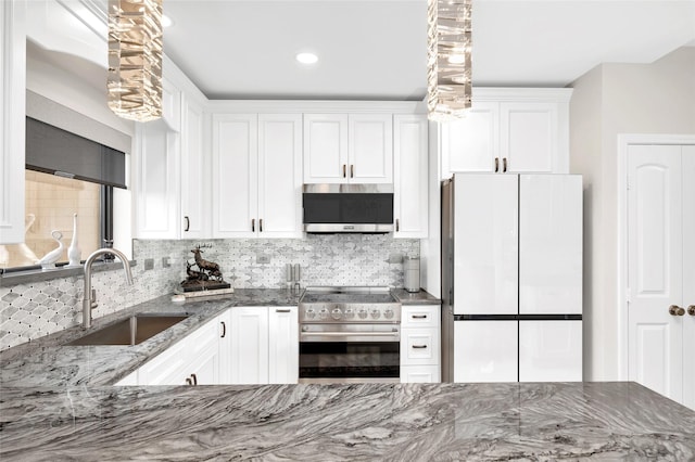 kitchen with appliances with stainless steel finishes, decorative backsplash, a sink, and white cabinets