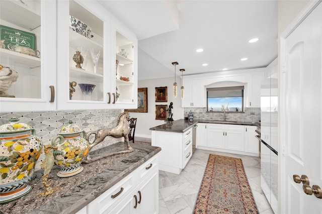 kitchen with dark stone counters, marble finish floor, a sink, and white cabinets