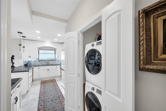 washroom with marble finish floor, stacked washer / drying machine, recessed lighting, a sink, and laundry area