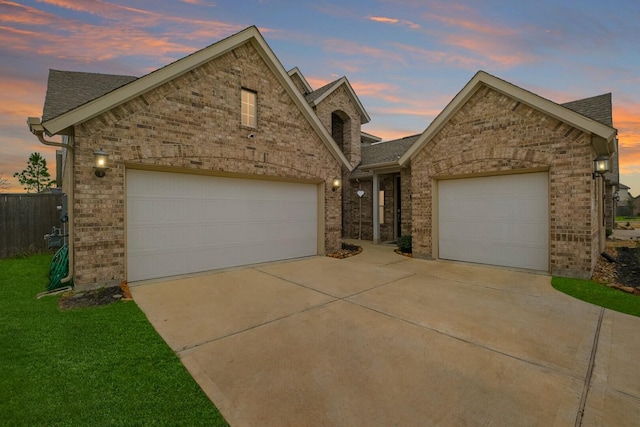 view of front of property with driveway, fence, a yard, a garage, and brick siding