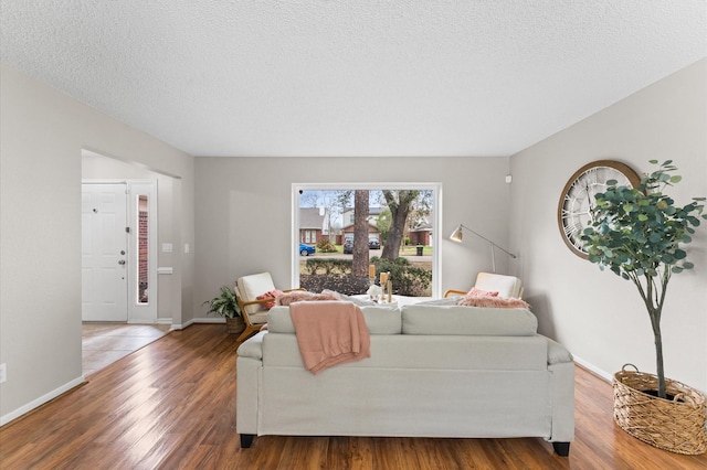 living area with a textured ceiling, baseboards, and wood finished floors