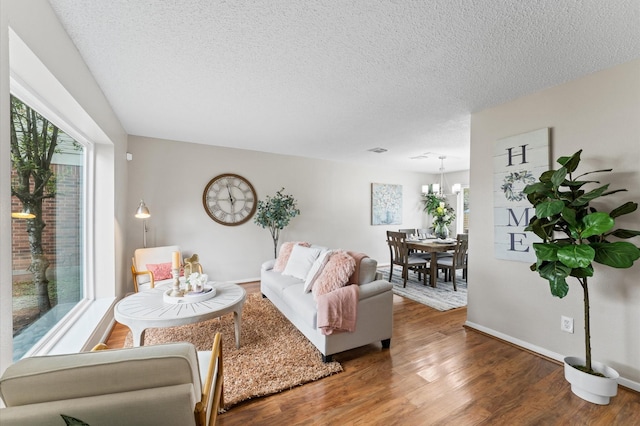 living room with visible vents, a textured ceiling, baseboards, and wood finished floors