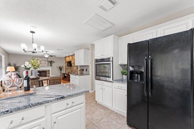 kitchen with light tile patterned floors, visible vents, a fireplace, stainless steel oven, and black fridge