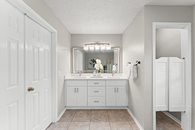 full bath featuring tile patterned flooring, double vanity, a textured ceiling, and a sink