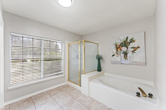 bathroom featuring tile patterned floors, a garden tub, a textured ceiling, a shower stall, and baseboards