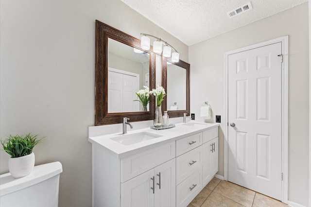 bathroom with visible vents, a sink, a textured ceiling, tile patterned floors, and toilet