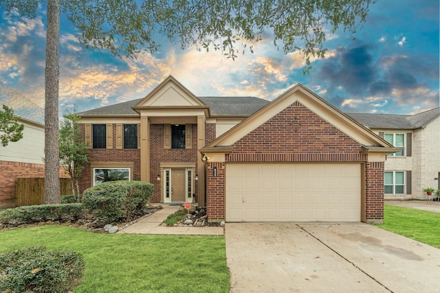 neoclassical home with a lawn, driveway, fence, an attached garage, and brick siding